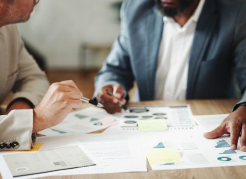 Hands, paperwork and discussion for business, colleagues and data analyst with charts for market research. Corporate, graphs and people with documents in office, teamwork and employees with info.